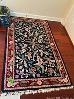 Full view of the rectangular wool accent rug laid flat on wooden floor, showing overall design and fringe.