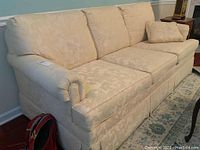 Front view of the sofa with cushions and matching throw pillow on a patterned rug.