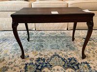 Full front view of the vintage solid wood coffee table showing carved cabriole legs and carved apron detail.