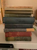 Stack of 11 vintage books showing a variety of sizes, colors and worn condition marks.