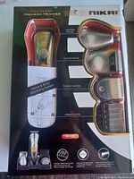 Front view of Nikai grooming kit in packaging showing trimmer and multiple attachments.