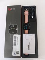 Boxed UOrit CS201 health and fitness smartwatch shown with pink strap, charger cable, and instruction manual.