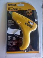 Front packaging view of a yellow Stanley Heavy Duty Glue Shot glue gun showing features and project uses