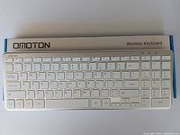 Photo of the OMOTION wireless keyboard showing full layout and condition of the item in white and silver.