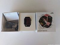Photo of smart watch in box along with charger and user manual.