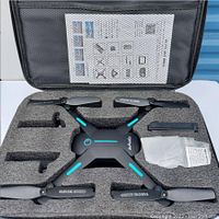 Zuhafa JY03 drone in protective foam packaging, showing the foldable drone with four propellers, a battery, and a manual inside a carrying case.