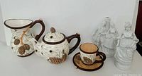Tea set with pine cone design including pitcher, teapot, cup and saucer