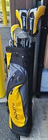 Yellow and black Acuity brand golf bag standing upright with golf club heads visible inside the top opening