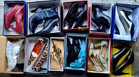 Top-down view of multiple pairs of women's heels and booties, various colors and styles, many in their original boxes.
