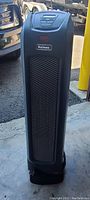Front view of black Holmes tower fan showing brand logo, front mesh grille, and top control panel.