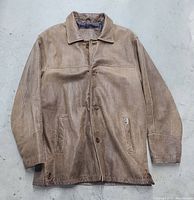 Front of light brown leather jacket with button closure and two side pockets, laid flat.