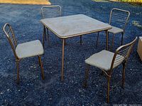 Full view of midcentury Cosco folding square table with four chairs set outdoors on gravel surface