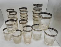 Full set of 15 textured dot glasses in three different sizes with silvertone rims arranged in rows.