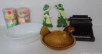 Photo showing amber glass hen dish, metal typewriter figurine, colorful Easter candles, and two wooden figurines