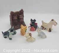 Photo shows six Scottie dog figurines in various colors including turquoise, yellow, red, cream, gray, beige, along with a textured brown sculpture behind them.