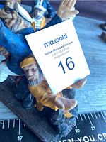 Close-up view of figurines with auction card showing number 16.