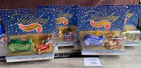All four Hot Wheels holiday special edition cars still in original packaging with snowflake themed blue and white backing and 'Holiday Hot Wheels' gold foil logo.