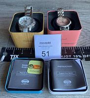 Two Fossil watches in respective tin boxes with instruction booklets and warranty cards in front, scale ruler, and lot card number 51 included.