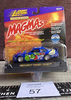Front view of boxed Johnny Lightning Magmas limited edition Yoshi Story diecast car showing colorful graphics and packaging condition.