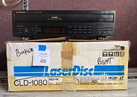 Front view of Pioneer CLD-1080 LaserDisc player atop its original box labeled 'LaserDisc' and model number CLD-1080 visible.
