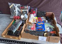 Full view of the toolbox cleaning mystery box with various hand tools and items packed in an open cardboard box on the floor.