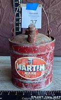 Front view of red vintage 4 quart Martin Wear oil can showing oval logo and spout