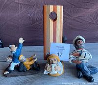 Three sailor figurines with wooden wine bottle holder piece in the background.