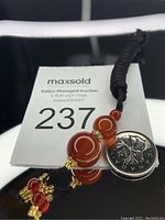 Photo showing the polished agate beads with red and gold accents alongside a Canadian quarter for size comparison