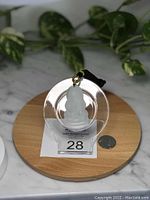Front view of translucent pale green Burma jade carved Buddha pendant displayed on a clear circular stand with a quarter coin for scale.