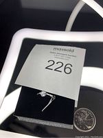 Photo showing the solitaire diamond ring with auction tag and a Canadian 25 cent coin for size reference.