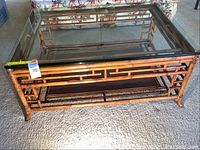 Full view of rectangular bamboo coffee table with glass top, placed on carpeted floor.