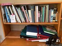 Books and binders on two shelves including binders stacked horizontally