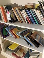 Image showing three shelves filled with assorted books of varied genres and sizes.