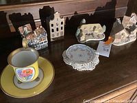 Overview photo showing yellow teacup and saucer, floral plate, and multiple ceramic figurines shaped like cottages and townhouses.