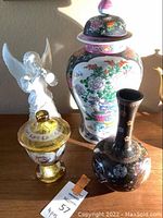 Photo showing three decor items: tall Asian vase, small dark ceramic vase, and glass angel figurine