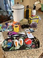 Photo of assorted decorative items, amethyst geode, binoculars, flashlight, batteries, fire extinguisher and notepads on countertop.