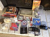 Overview of lot including cameras, decor items, books, and boxed heating pad