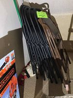 Side view of six folding chairs stacked together, five are black and one is brown, showing the color difference as noted by seller.