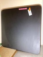 Top view of the square folding table surface with a price sticker and measurement label.