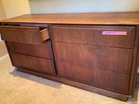 Front and side angle view showing walnut veneer finish, drawer alignment and integrated finger pulls, one top drawer open