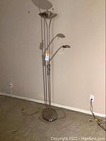 Full view of tall modern brushed metal standing floor lamp with bowl uplight and flexible reading lamp arm on a weighted base.