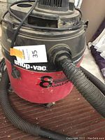 Photo of Shop-Vac wet dry vacuum showing the 8-gallon red tank, attached hose, and power cord with visible signs of use.
