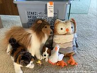 Photo showing a collection of stuffed animals including collie dog, owl, calico cat, husky dog, white goose, and chick toys.