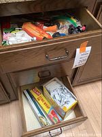 Photo showing two wooden drawers; the bottom drawer is open displaying a box of Glad Cling Wrap 200 sq ft and a box of small individually wrapped hand wipes. The upper drawer is partially open showing various small tools and other items.
