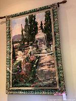 Full view of large scenic tapestry hung on wall, showing garden path, trees, flowers, and temple.