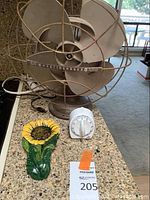 Shows front view of vintage Westinghouse fan, sunflower spoon rest, and kitchen timer on kitchen countertop.