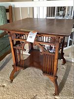 Full view of the vintage cherry wood parlor table with carved details on apron and turned legs with casters.