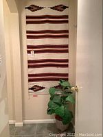 Full view of southwestern style wall hanging and faux plant next to door