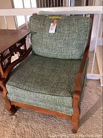 Wooden armchair with green check patterned upholstered cushions, showing front angle with wooden frame, armrests, seat and back cushions.