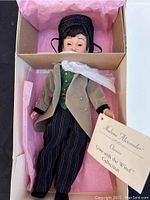 View of Madame Alexander doll packaged in original box with pink tissue paper, showing the full doll dressed in period clothing and box interior wear.